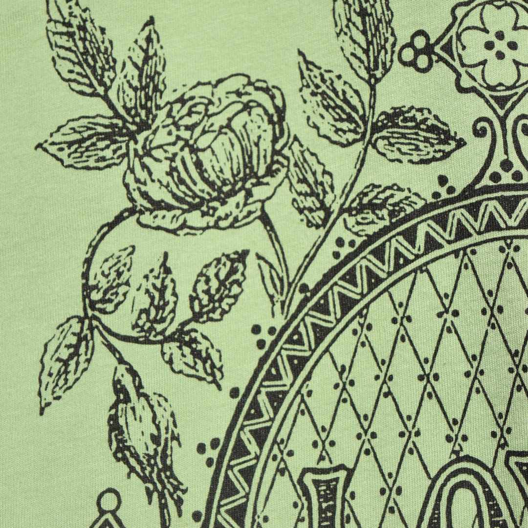 Close-up of black screen-printed filigree, antique roses, leaves and the word "Love" on a light green t-shirt from Rare Breed Organic Apparel.
