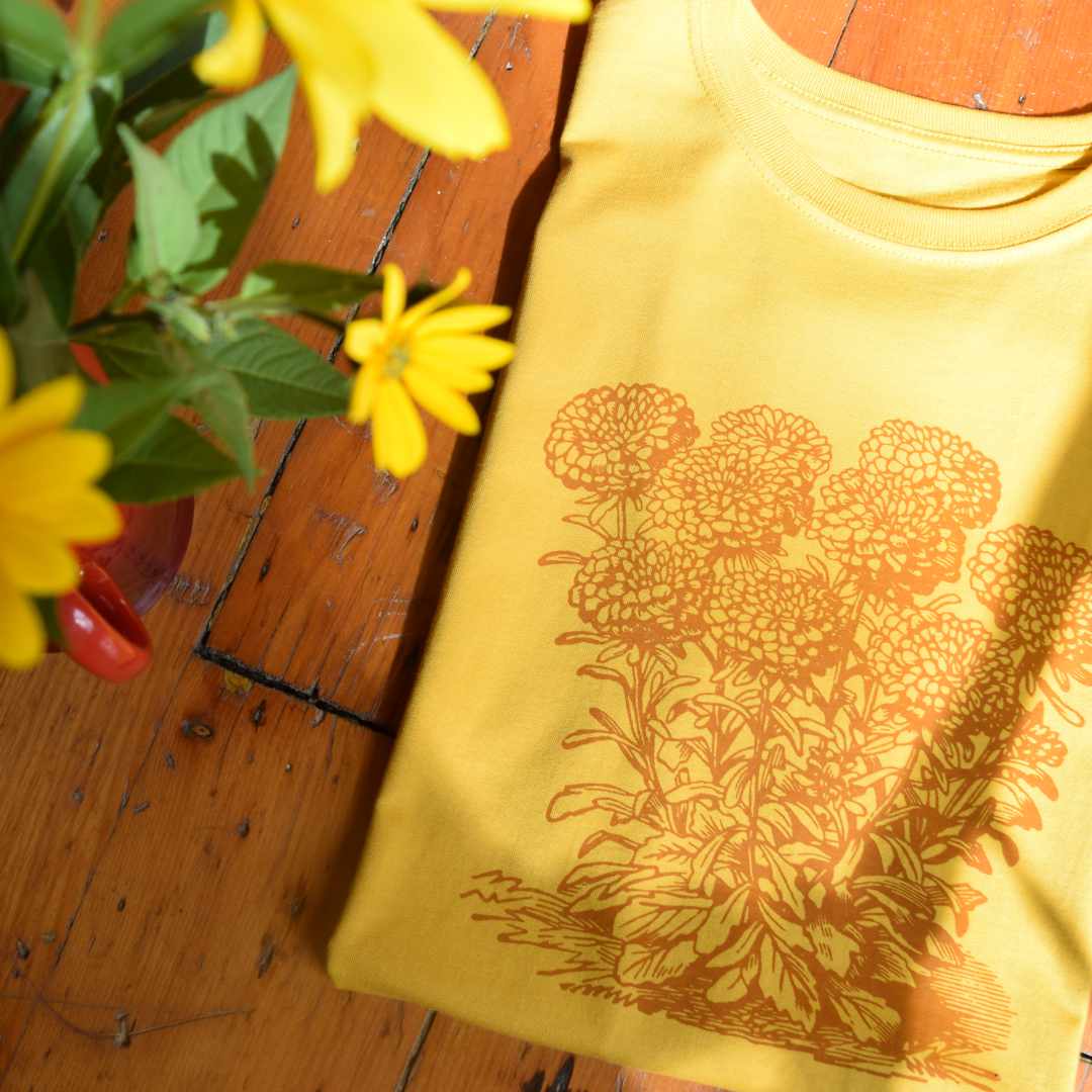 A yellow organic cotton t-shirt featuring a marigold graphic, lovingly restored from a vintage illustration by Rare Breed.