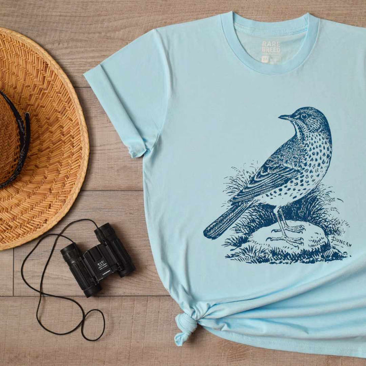 A T-shirt for birdwatchers!  Rare Breed's sky blue organic cotton t-shirt features a navy blue historically inspired bird graphic.  Organic T-shirt for birders featuring a vintage song bird design. Light blue T-shirt ethically made in USA. Image by Rare Breed Organic Apparel.